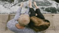 Man and Women sitting by the ocean and hugging after finding out how to stop hair loss